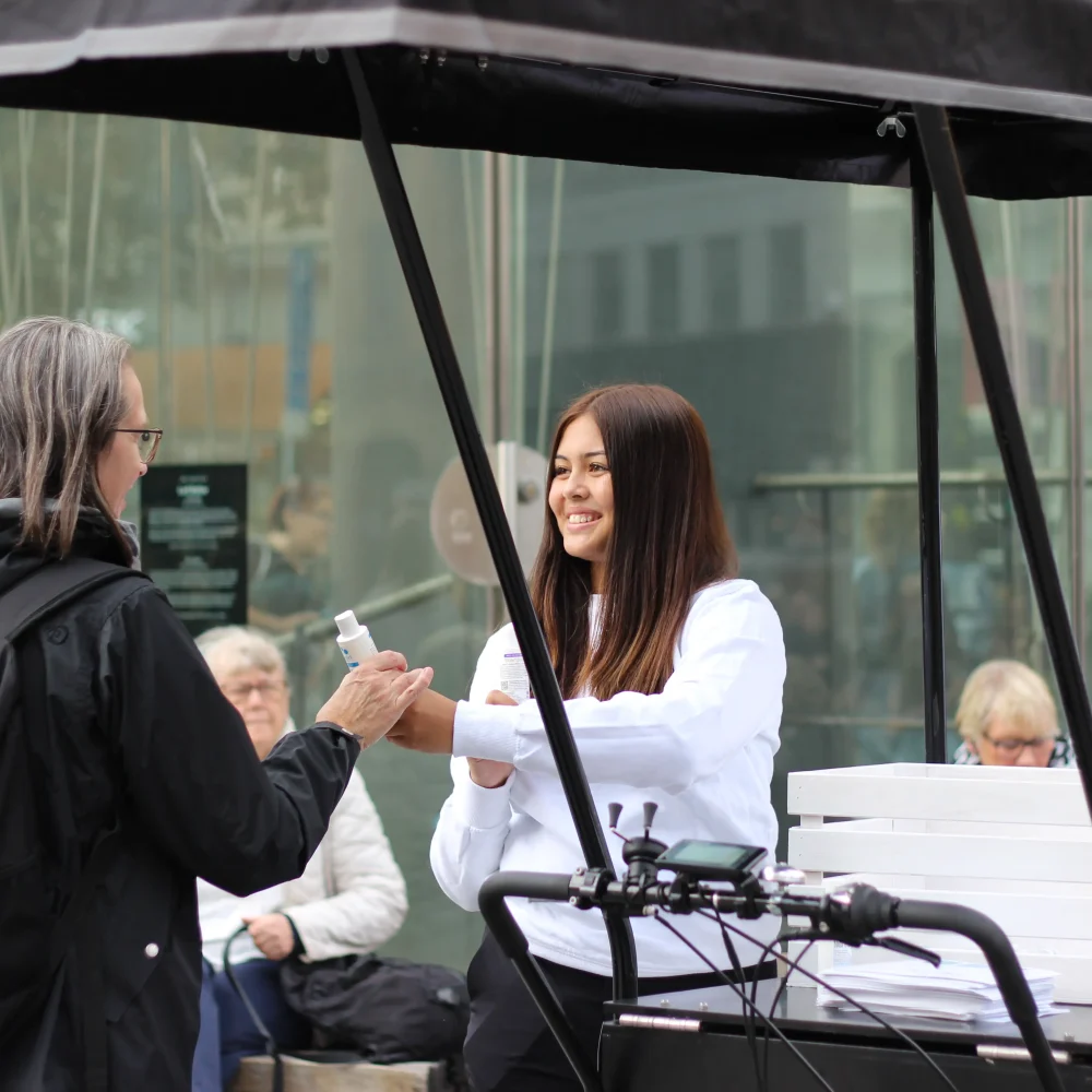 Eventpersonal delar ut produktsample till kvinna